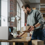 Απεικονίζεται ένας άνδρας ο οποίος κρατά ένα δέμα και εκτυπώνει ετικέτα από έναν θερμικό εκτυπωτή.